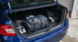 Compact collapsible wheeled golf bag folded down for easy trunk storage in a sedan