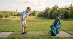 A young boy practising his golf swing at a driving range in Ontario with his lightweight junior golf bag for kids nearby.